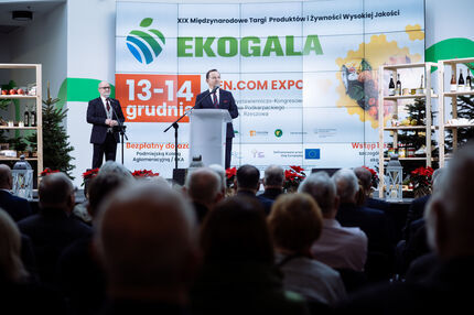 Marszałek przemawia z mównicy podczas XIX Międzynarodowych Targów Produktów i Żywności Wysokiej Jakości EKOGALA, odbywających się 13–14 grudnia w Centrum Wystawienniczo-Kongresowym Województwa Podkarpackiego w Rzeszowie. W tle widoczny ekran z informacją.