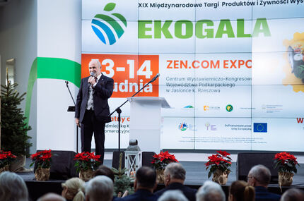 Konferansjer w garniturze przemawia przy mównicy podczas EKOGALI — XIX Międzynarodowych Targów Produktów i Żywności Wysokiej Jakości, odbywających się 13–14 grudnia w Centrum Wystawienniczo-Kongresowym Województwa Podkarpackiego w Jasionce k. Rzeszowa. 